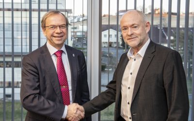 To menn som håndhilser og ser inn i kamera